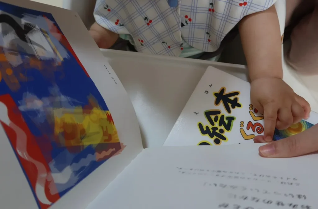 赤ちゃんがアート絵本を見ながら指さしする様子（対話型鑑賞・VTSの実践イメージ）