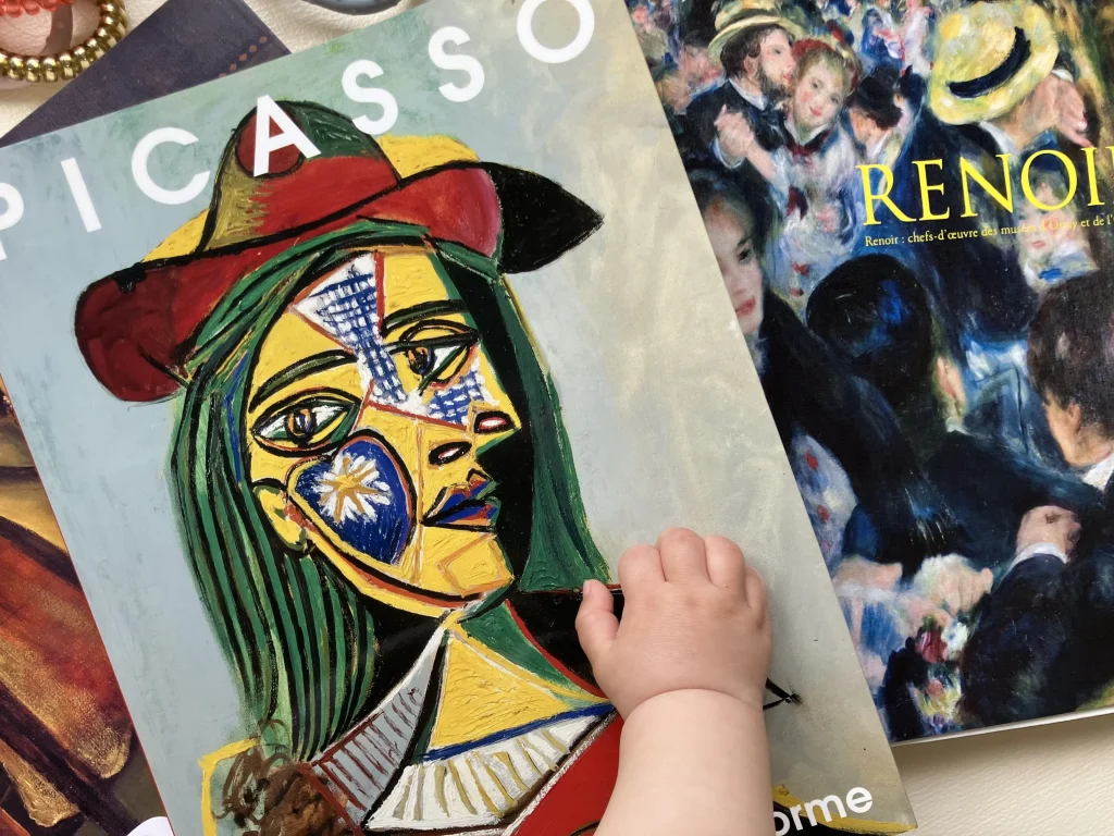 赤ちゃんがピカソの画集に手を伸ばし、おうちでアート鑑賞をしている様子