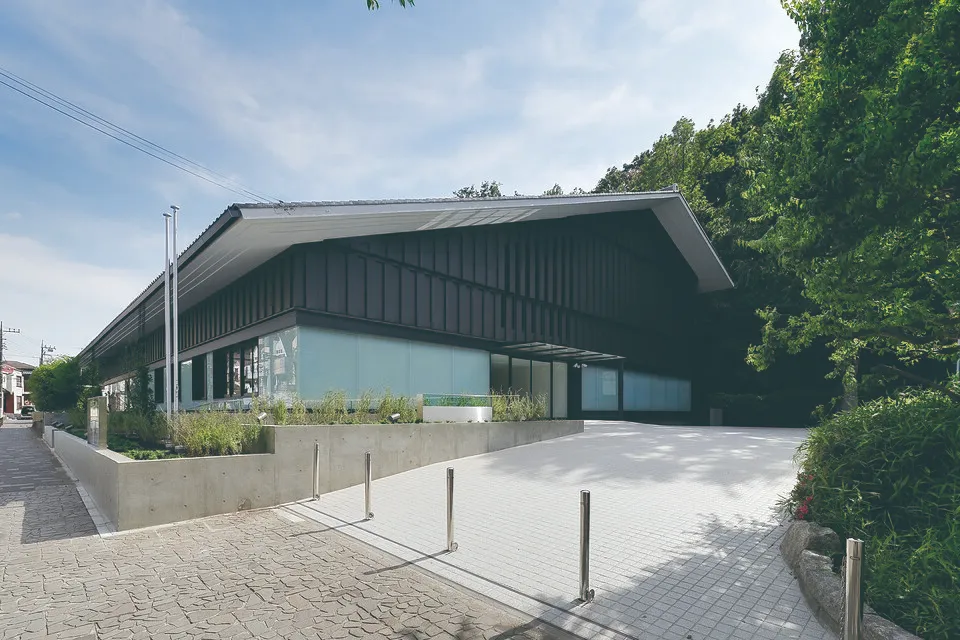 板橋区立美術館の外観。低層の建物と周囲の緑、前面のアプローチが見える